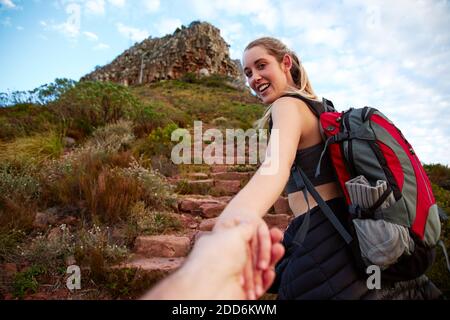 Punto di vista di una giovane donna attiva che camminano lungo percorso in campagna incoraggiando off screen partner a seguirla tenendo la mano Foto Stock
