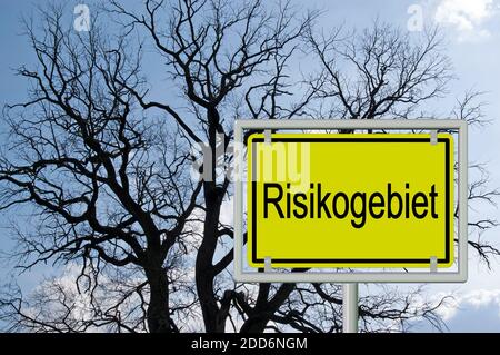Segno del nome della località con la parola "Risikogebiet", tradotta "area di rischio" davanti a una silhouette ad albero Foto Stock