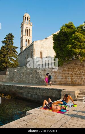 Isola di Hvar, turisti prendere il sole di fronte al Monastero Francescano, Hvar Town, Croazia Foto Stock