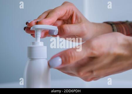 Donna che strizza il gel antisettico sul palmo, pulendo le mani - primo piano Foto Stock