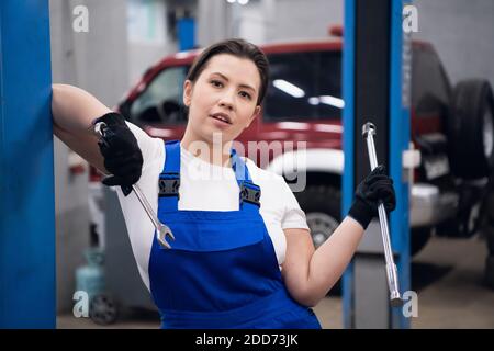 Un meccanico in tute da lavoro tiene una chiave nelle sue mani. Scatto medio Foto Stock