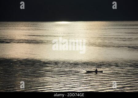 Pescatore in una barca da pesca sul lago Toba (Danau Toba) all'alba, Sumatra settentrionale, Indonesia, Asia Foto Stock