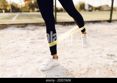 Donna sportiva che fa esercizi con elastico per il fitness, all'aperto nel parco Foto Stock