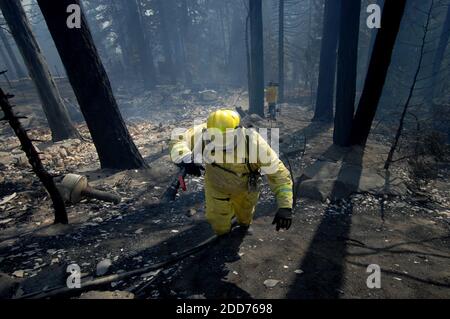 NESSUN FILM, NESSUN VIDEO, NESSUNA TV, NESSUN DOCUMENTARIO - Richard Valenzuela, un pompiere con l'Imperiale Task Force, trasporta un tubo flessibile per estinguere i punti caldi attraverso i resti di una casa al largo di Wilderness Road a Running Springs, CA, USA, il 23 ottobre 2007. Foto di Kevin German/Sacramento Bee/MCT/ABACAPRESS.COM Foto Stock