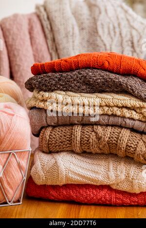 Mucchio di abiti di lana beige su sfondo bianco. I pullover e le sciarpe a maglia calda sono piegati in un unico mucchio. Foto Stock