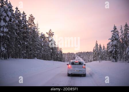 Auto che guida su strade ghiacciate innevate su una strada Viaggio durante il viaggio in Lapponia all'interno del Circolo polare Artico in Finlandia Foto Stock