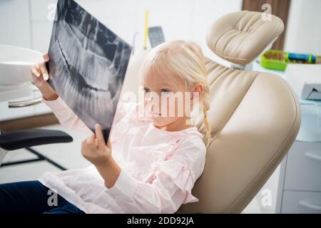 Una bambina esamina una radiografia panoramica dei denti di alcuni pazienti. Foto Stock