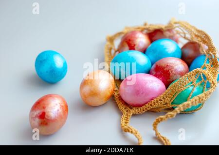 uova multicolore in una borsa a maglia Foto Stock