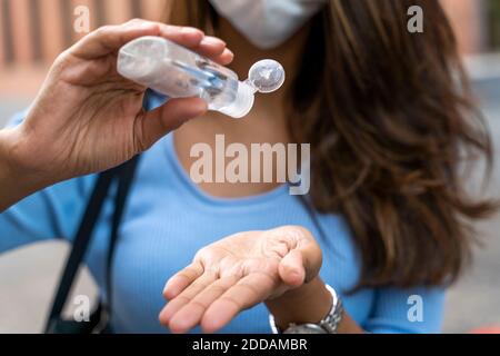Donna d'affari che versa l'igienizzatore a portata di mano durante la pandemia Foto Stock