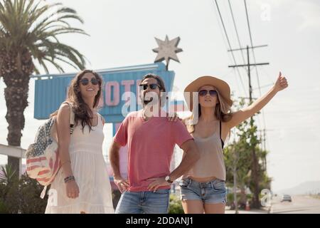 Amici di sesso maschile e femminile in occhiali da sole che salutano un giro durante giorno di sole Foto Stock