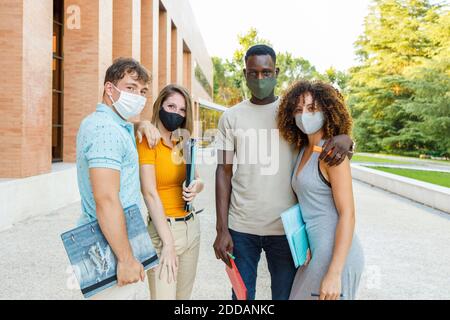 Gli studenti universitari indossano una maschera protettiva mentre si trovano in un campus Foto Stock