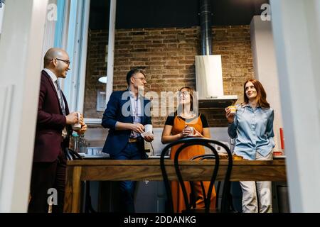 Vista ad angolo basso di imprenditori maschili e femminili che discutono mentre avere caffè in cucina d'ufficio Foto Stock