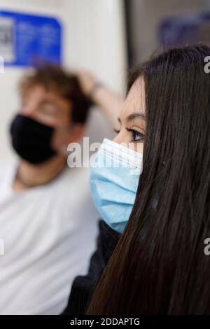 Giovane coppia che indossa una maschera protettiva che viaggia in treno Foto Stock