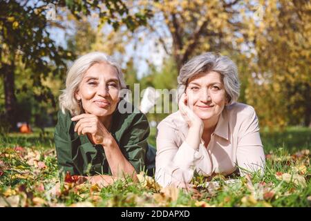 Sorridi le donne che guardano via mentre si stendono sull'erba al parco Foto Stock