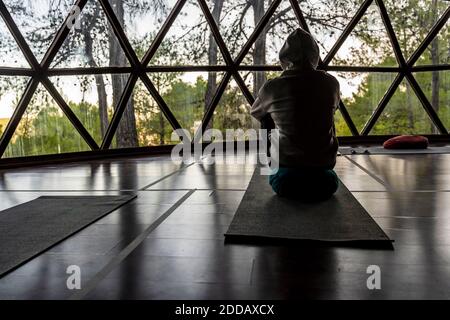 Uomo turista che indossa cappuccio seduto su tappetino per esercizi a salute ritiro Foto Stock