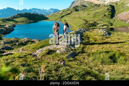 Padre e madre che portano figlie mentre non si guarda lakeshore in giornata di sole Foto Stock