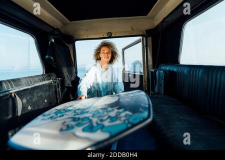 Giovane donna che rimuove la tavola da surf dall'auto mentre si trova in spiaggia Foto Stock