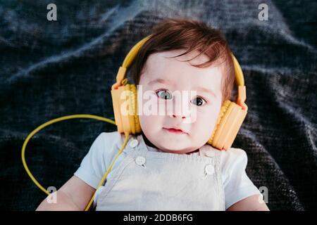 Bambino che indossa le cuffie stesi su una coperta all'aperto Foto Stock