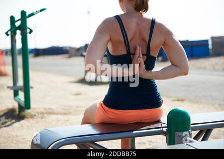 Donna matura che fa pashchima namaskarasana posizione mentre si siede sul pavimento Foto Stock