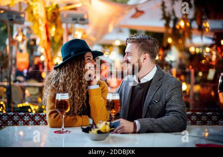 Coppia che parla mentre si siede alla birreria all'aperto in città Foto Stock
