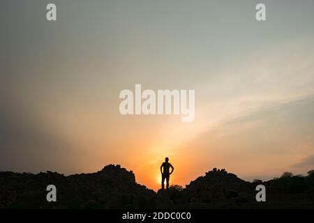 Silhouette di persona che ammira il sole che tramonta Foto Stock