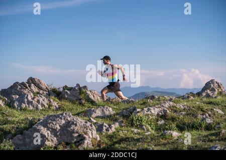 Sportivo che corre in montagna contro il cielo limpido Foto Stock