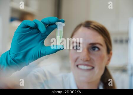 Donna sorridente che guarda il testubo mentre si tiene in mano a. laboratorio Foto Stock
