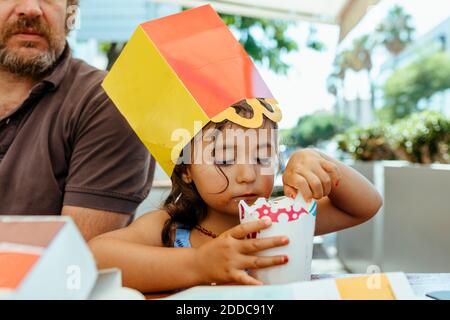 Ragazza carina che mangia gelato mentre si siede con il padre a. ristorante Foto Stock