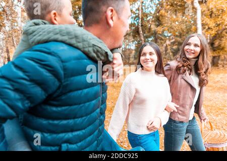 Felice madre e figlia che camminano mentre il padre porta il figlio piggyback Nel parco di Cannock Chase Foto Stock