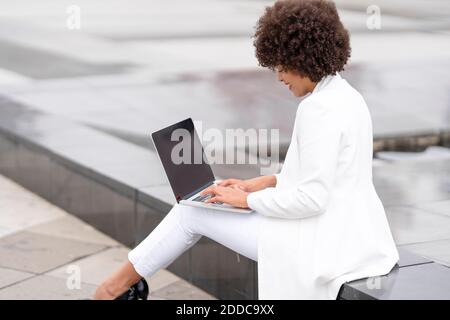 Donna d'affari che lavora su un computer portatile mentre si siede all'aperto Foto Stock