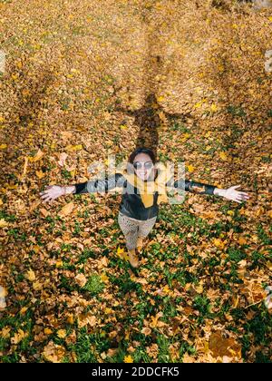 Sorridente bella donna con le braccia allungate godendo autunno al parco Foto Stock