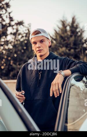 Giovane uomo in piedi dalla porta aperta dell'auto Foto Stock