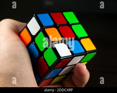 Il cubo di Rubik in mano su uno sfondo scuro Foto Stock