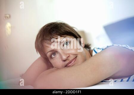 Donna premurosa che guarda via mentre si sdraiava in camera da letto a. casa Foto Stock