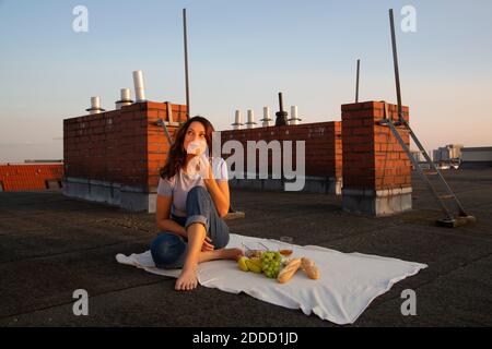 Giovane donna premurosa che ha frutta durante il picnic sul tetto Foto Stock