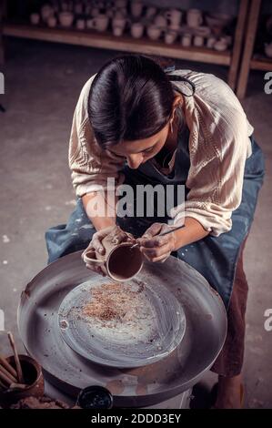 Un bel vasaio professionale dimostra il processo di produzione di piatti in ceramica utilizzando la vecchia tecnologia. Ispirazione e creatività. Foto Stock