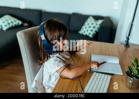 Donna che indossa le cuffie alla scrivania Foto Stock