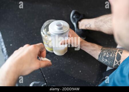 Primo piano di sportivi che tengono frullato proteico mentre si siede in palestra Foto Stock