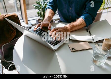 Freelance maschile che lavora su un computer portatile al tavolo nel bar Foto Stock