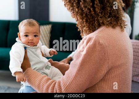 Madre che tiene la figlia del bambino mentre si siede a casa Foto Stock