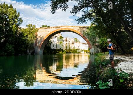 Uomo in piedi e guardando l'antico ponte della Concordia a Fossombrone, Marche, Italia Foto Stock