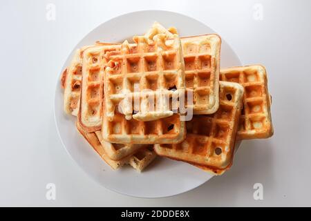 Waffle semplici su un piatto mentre su sfondo bianco Foto Stock