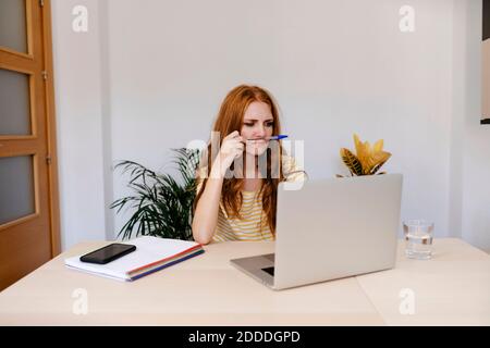 Donna premurosa che usa il notebook mentre lavora a casa Foto Stock