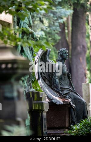 Statua di angelo intemperie seduto al bordo della tomba in cimitero Foto Stock