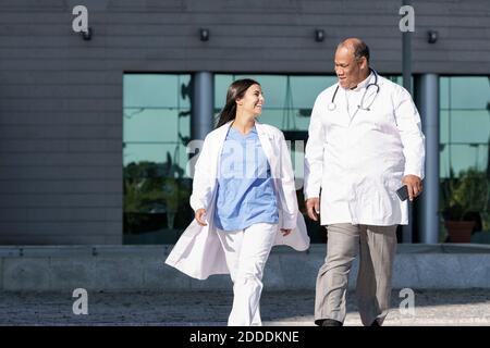 Medici che indossano camice da laboratorio che cammina contro l'ospedale Foto Stock