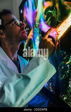 Scienziato maschile che punta alla proiezione del cervello umano con nervo esame delle fibre in laboratorio Foto Stock