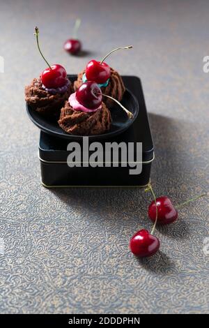 Mini gugelhupf con crema per torte colorata e ciliegie Foto Stock