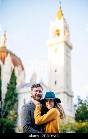Coppia sorridente che si erge insieme contro la chiesa Foto Stock