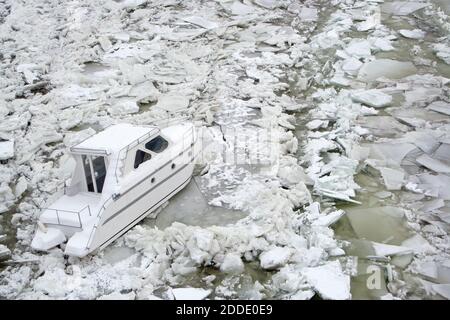 Primo piano di una piccola barca bianca intrappolata in un fiume ghiacciato Danubio a Novi Sad,Serbia.condizioni meteorologiche difficili in inverno. Foto Stock