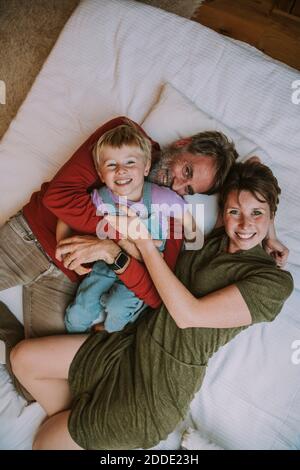 Madre, padre e figlio si abbracciano mentre si stendeva a letto a casa Foto Stock